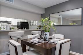A modern dining room with a dark wood table and white chairs.