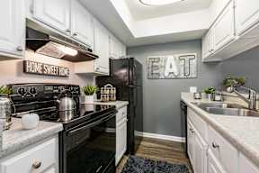 A kitchen with a black stove top oven and a black refrigerator.