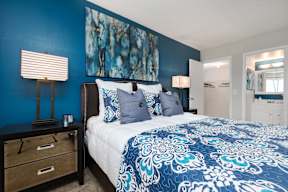 A bedroom with a bed, nightstand, and lamp.