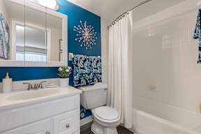 A bathroom with blue walls and white fixtures.