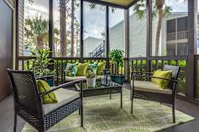 A patio with a table and chairs with a view of a house and trees.