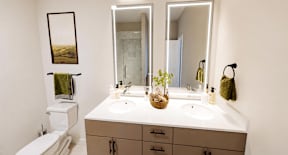 A bathroom with a toilet, sink, and mirror.