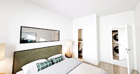 A bedroom with a bed, a lamp, and a mirror on the wall.