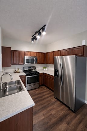 A kitchen with a stainless steel refrigerator, oven, and sink.