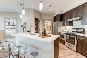 One Bedroom Apartments in Chandler AZ - The Core Chandler - Modern Kitchen with Stainless Steel Appliances, Quartz Countertops, Wood-Style Cabinets, and Large Kitchen Island