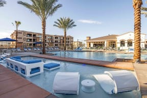 Apartments in Chandler AZ-The Core Chandler Resort-Style Swimming Pool Surrounded by Lounge Chairs, Palm Trees, and a Separate In-Water Seating Area