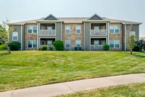 an apartment building with a lawn and a sidewalk in front of it