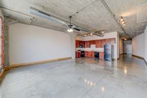A large, empty room with a concrete floor and ceiling, and a red brick wall on the left side.