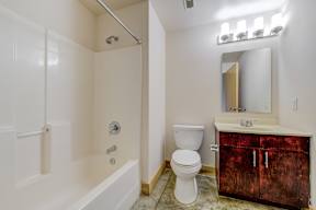 A white bathroom with a wooden cabinet and a white toilet.