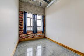 A room with a brick wall and a window with blue curtains.