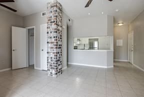 A kitchen area with a white tile floor and a brick pillar.
