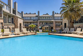 A large swimming pool in front of a building with a palm tree.