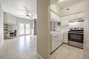 A kitchen with a stove top oven and a fan.