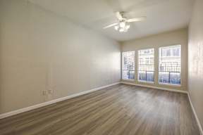 A room with a ceiling fan and wooden flooring.