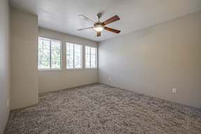 A room with a ceiling fan and carpeted floor.