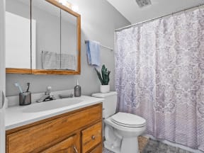 a bathroom with a white sink and toilet next to a shower with a purple shower curtain