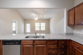 an empty kitchen with granite counter tops and wooden cabinets