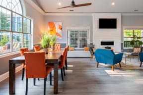 a living and dining room area with a large wooden table and orange and blue chairs
