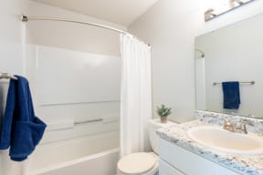 a bathroom with a white shower curtain and a white toilet next to a sink with a blue
