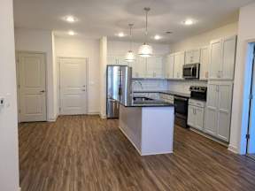 A kitchen with a white island and wooden floors.