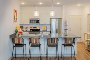 A kitchen with a refrigerator, microwave, oven, and sink.