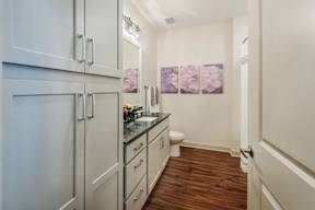 A kitchen with white cabinets and a wooden floor.