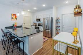A kitchen with a black countertop and stainless steel appliances.