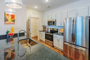 A kitchen with a stainless steel refrigerator and a granite countertop.