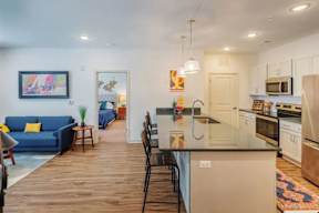 A kitchen with a blue couch and a painting on the wall.