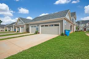 A row of houses with a blue trash bin in front of the garage.