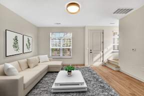 A living room with a beige couch, a white coffee table, and two framed pictures on the wall.