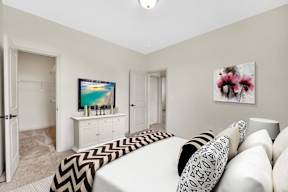 A living room with a white couch and a television on a white cabinet.