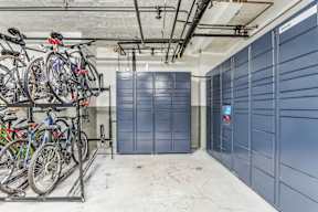 A bike rack with several bicycles is in front of a wall of blue lockers.