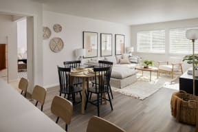 an open concept living room and dining room with white walls and hardwood floors