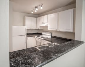 a kitchen with granite countertops and white appliances