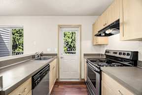 A kitchen with a stove, sink, and cabinets.