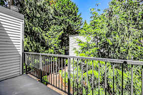 A balcony with a metal railing overlooks a lush green forest.
