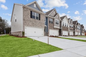 a row of houses with white garage doors and a green lawn
