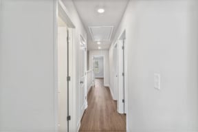 a long hallway with white walls and wood floors