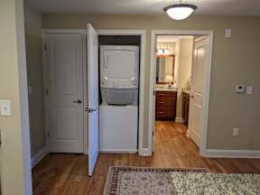 A small white fridge is in a narrow hallway.