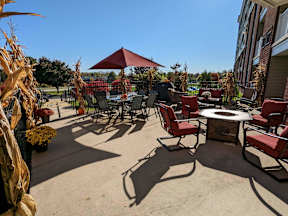 A patio with a table, chairs, and a red umbrella.