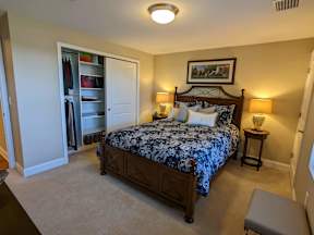 A bedroom with a bed, nightstands, and a closet.