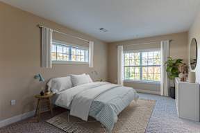 A bedroom with a bed, nightstand, and window.