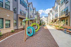 A playground with a slide in the middle of a walkway between buildings.