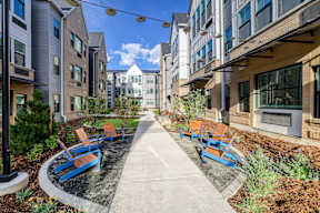 A row of blue benches are lined up on a concrete walkway.