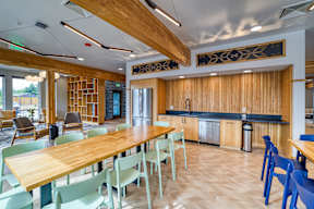 A modern kitchen with a long wooden table and blue chairs.
