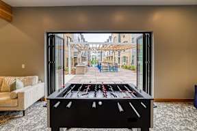 A foosball table is in the middle of a room with a couch and a chair.