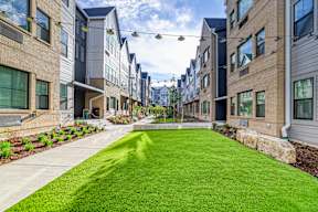 A row of modern townhouses with a green lawn in the foreground.
