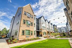 A modern apartment complex with a well-maintained lawn in front.