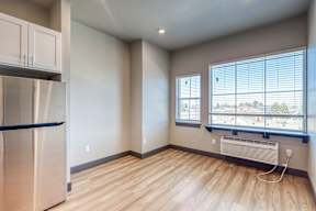 A kitchen with a stainless steel refrigerator and wooden floors.